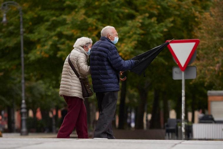 Dos personas pasean por la calle con la mascarilla puesta.