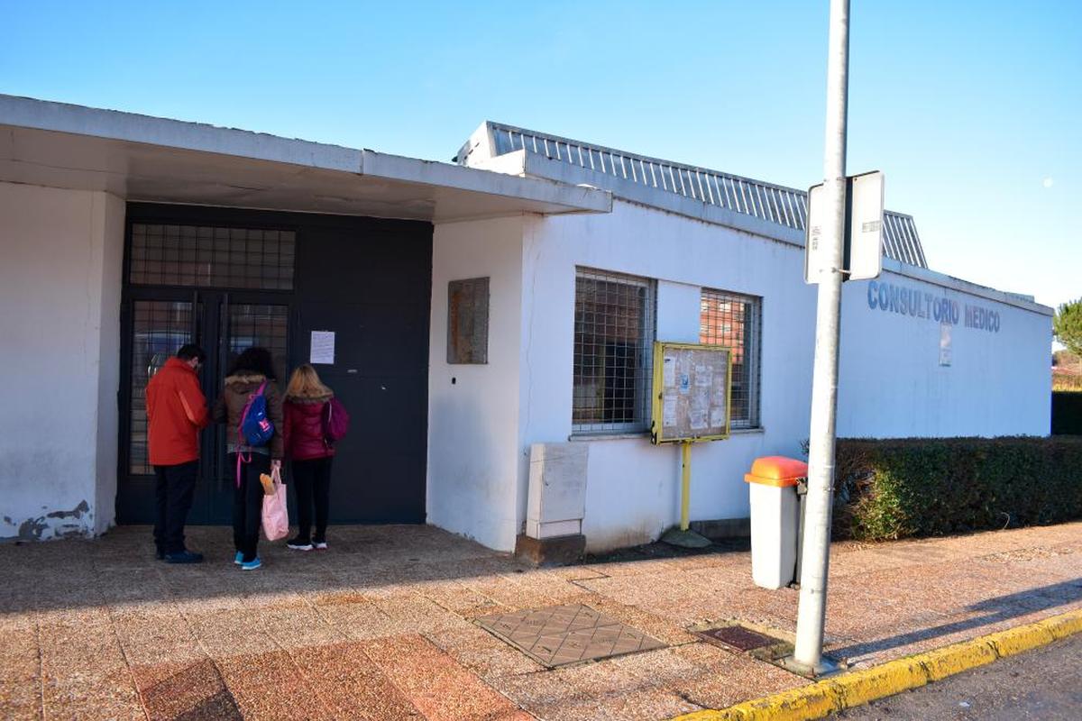 Vecinos de la urbanización El Encinar informándose del cierre del consultorio médico por un cartel.