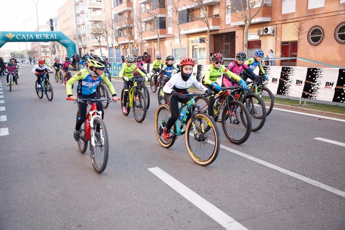 Un pelotón de jóvenes ciclistas recorre las calles de Salamanca durante una carrera.