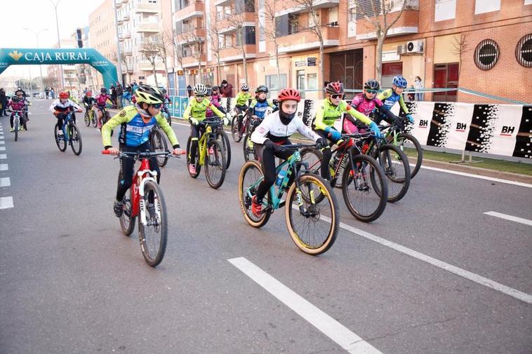 Un pelotón de jóvenes ciclistas recorre las calles de Salamanca durante una carrera.