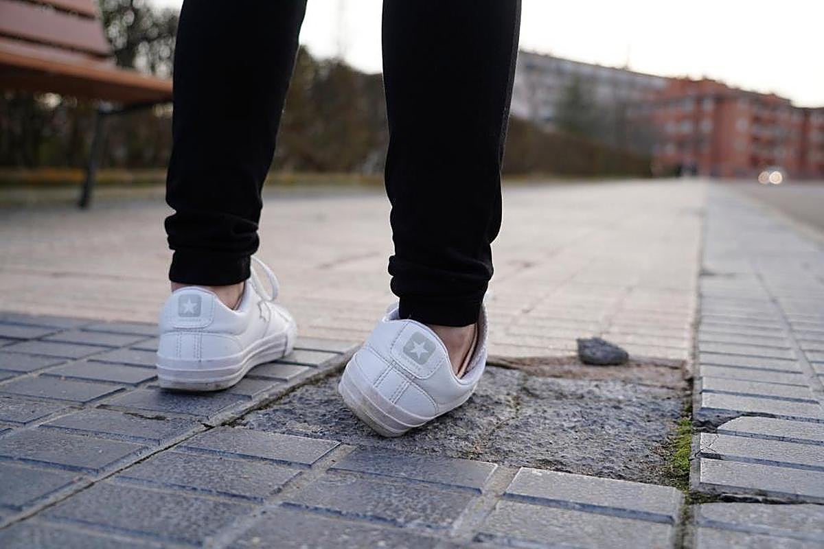 Una mujer da un traspié con una baldosa en mal estado.