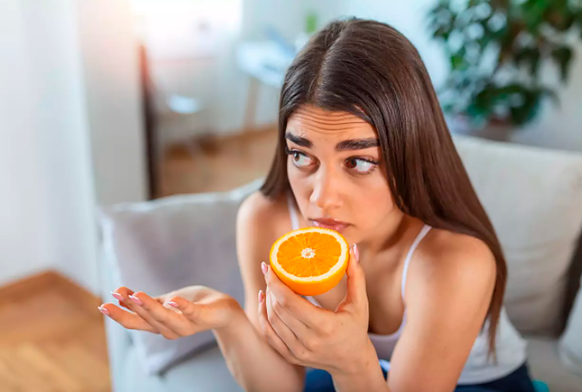 Una joven intenta oler una naranja