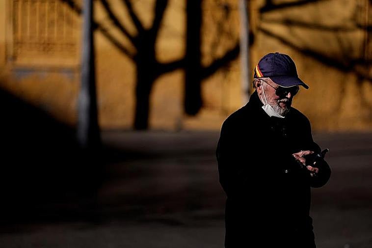 Un hombre con la mascarilla bajada consulta el móvil