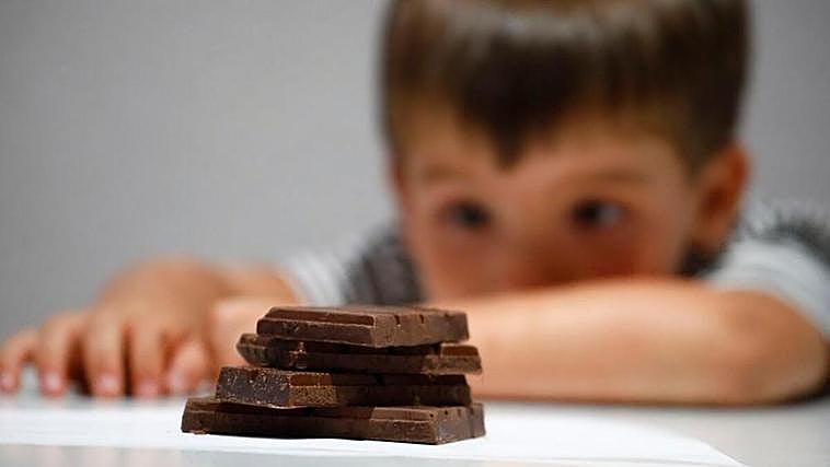 Un niño delante de varios trozos de chocolate.
