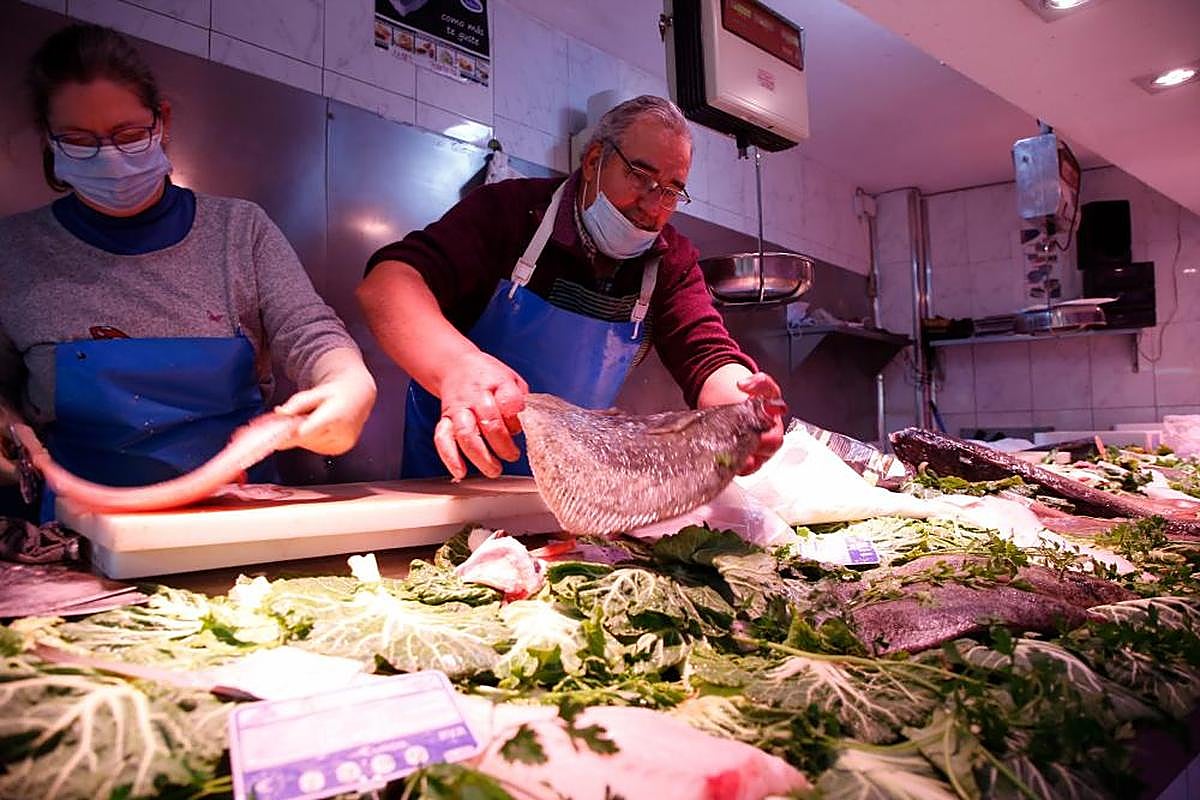 Dos pescaderos preparan sendos pedidos en un establecimiento de la ciudad