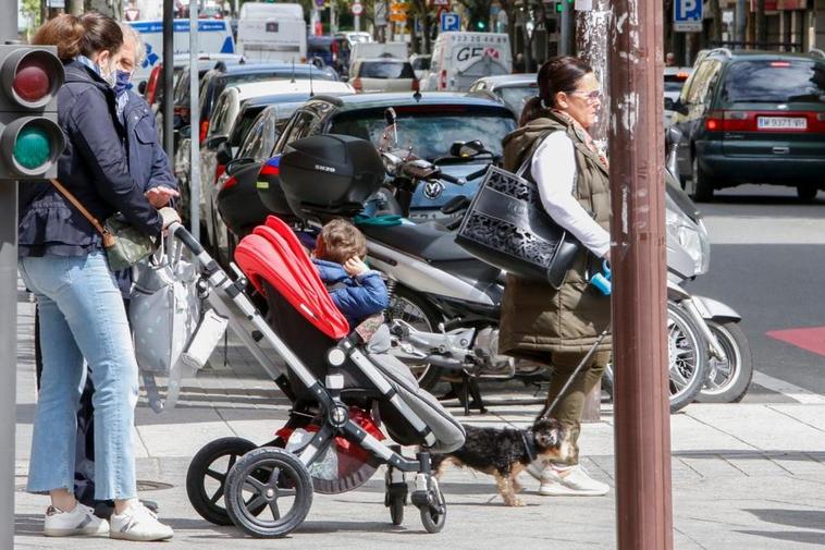 Una mujer llevando en un carrito a un menor de corta edad