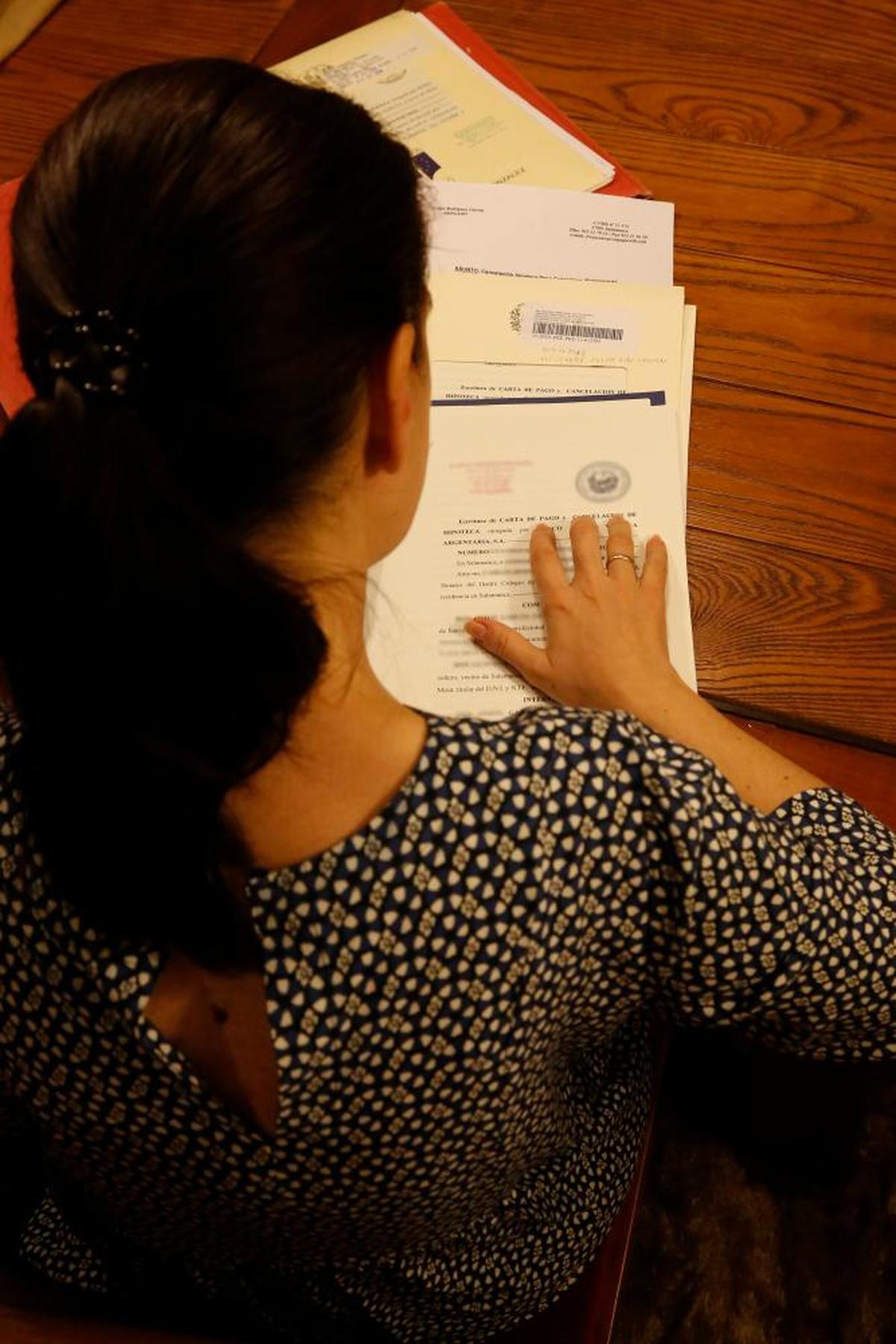 Una mujer revisando la documentación para la transmisión de una vivienda.