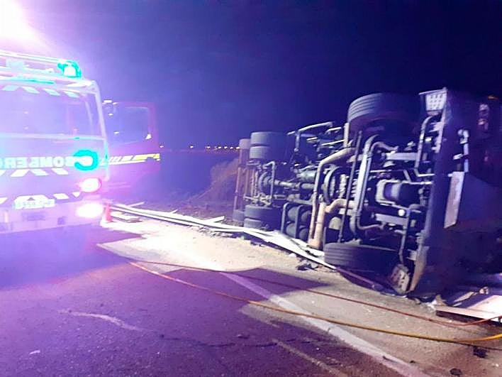 El camión de basura, volcado junto a una dotación de los bomberos.
