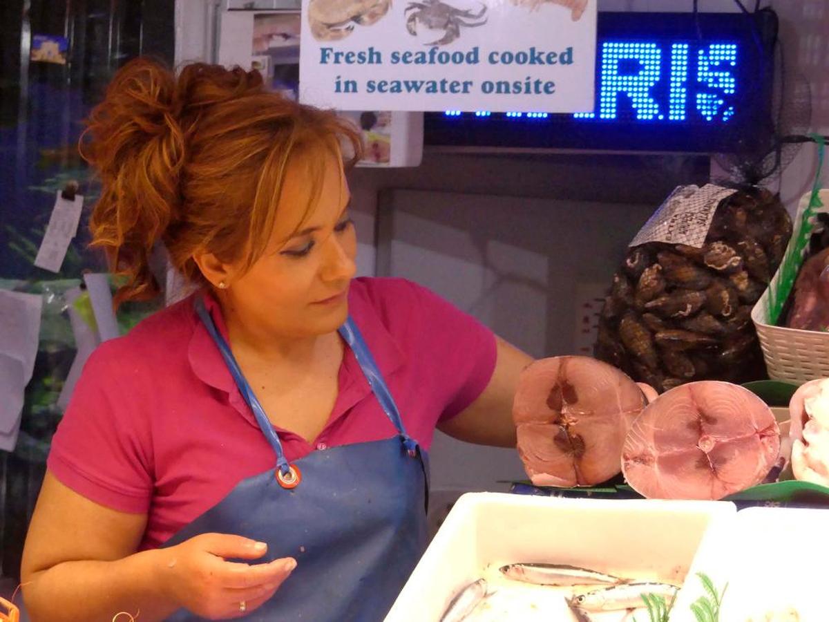 Una pescadera coge una de las piezas de bonito, que llegó hace dos semanas a los mercados