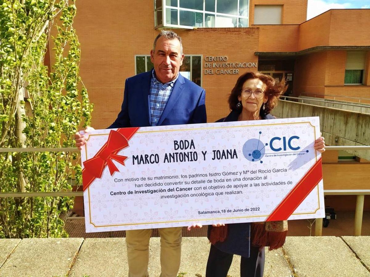 Los padrinos, con el cheque, posan delante del Centro del Cáncer.