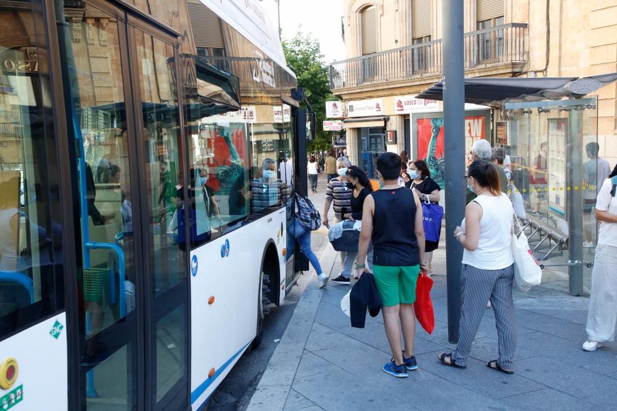 Varias personas subiendo a un autobús urbano en la ciudad.