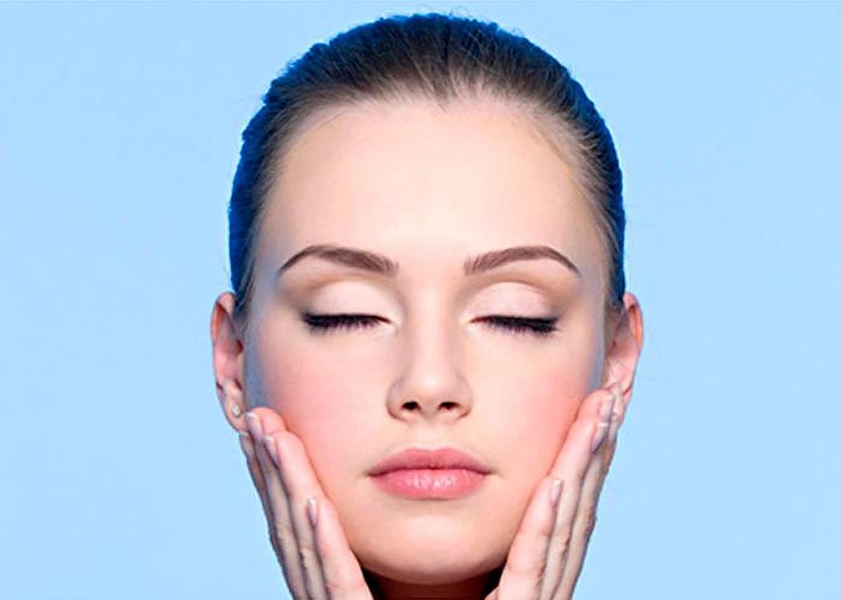 Una mujer practicando el yoga facial