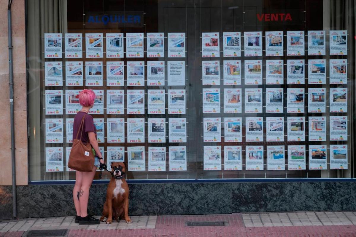 Una joven mira la oferta de pisos de una inmobiliaria