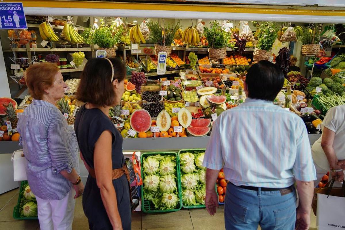 Varios clientes hacen cola para comprar en un puesto del mercado.