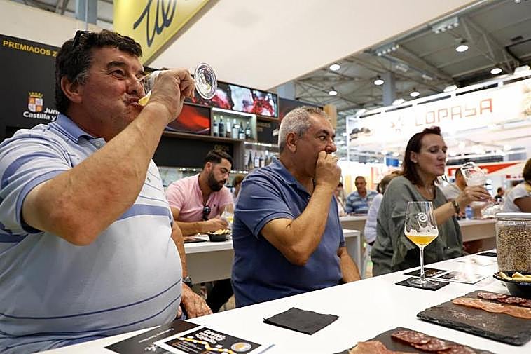 Varias personas almuerzan embutido y beben cerveza de manera gratuita en los stands.