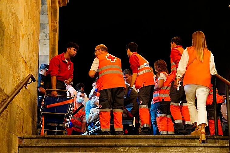 Voluntarios de Cruz Roja atienden a una mujer mareada junto a las escaleras de la plaza del Mercado.