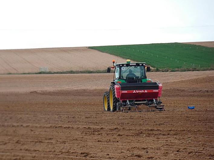 Un agricultor laborea la tierra con su tractor.
