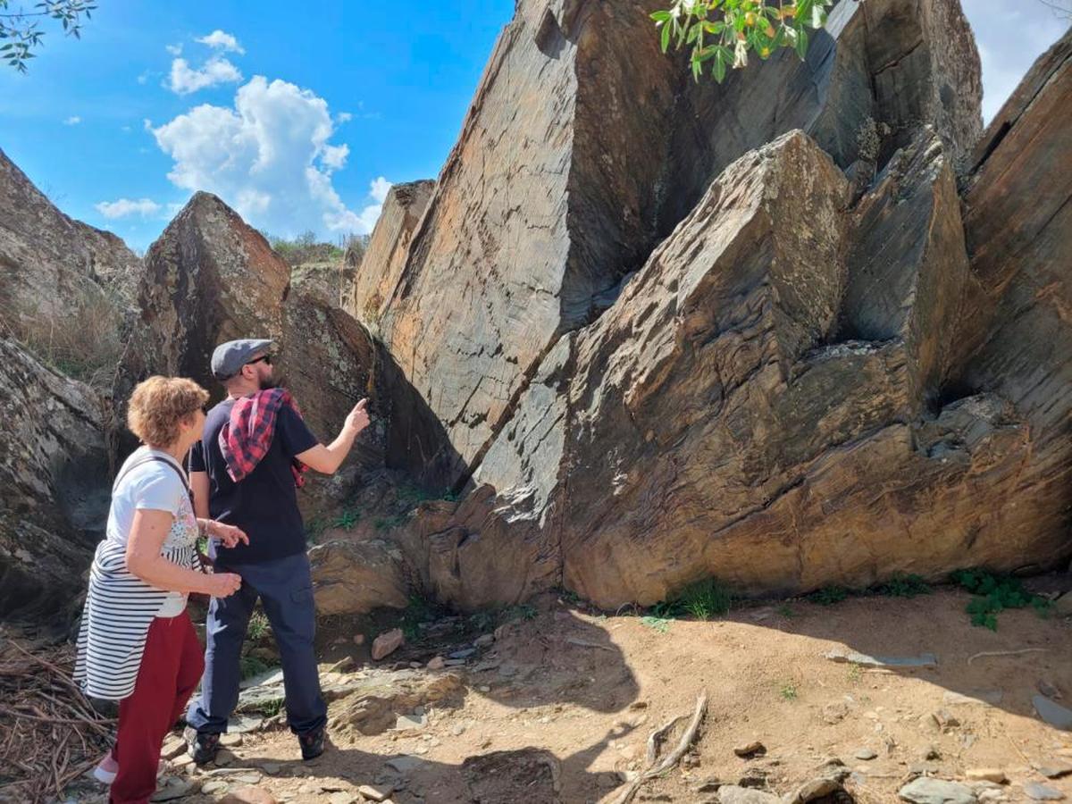 Visitantes ante uno de los paneles con grabados rupestres del yacimiento Patrimonio de la Humanidad