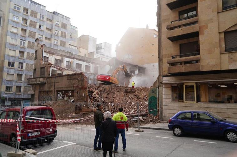 Trabajadores y viandantes observan el derribo del edificio