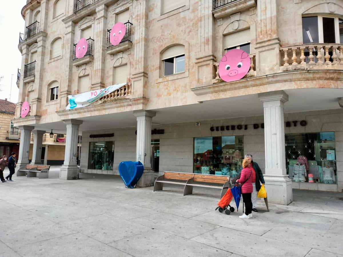 La Plaza Mayor con vecinos realizando sus compras y el cartel de la campaña “Yo compro en Guijuelo” en el balcón