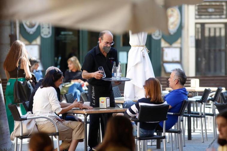 Un camarero atiende a clientes en una de las terrazas situadas en el centro de Salamanca.