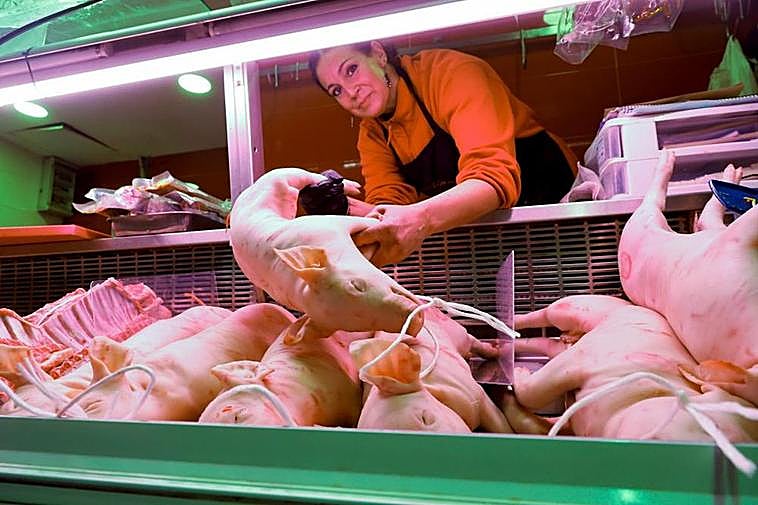 Raquel Macías, en su carnicería, saca tostones de la cámara.  ALMEIDA