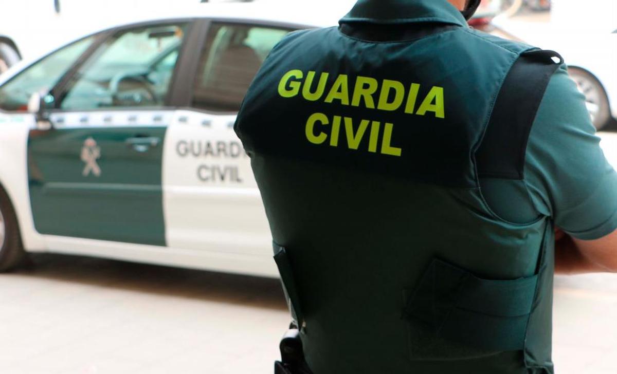 Un agente de la Guardia Civil junto a su vehículo.