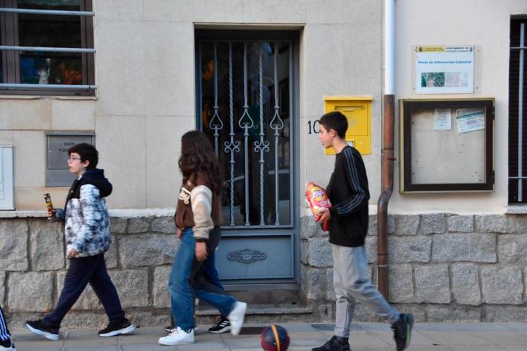 Tres jóvenes pasan ante el buzón de Correos instalado en la Casa Consistorial de Castellanos de Moriscos