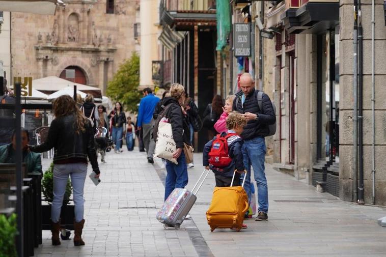 Una familia de visitantes, con sus maletas por la Rúa. LAYA