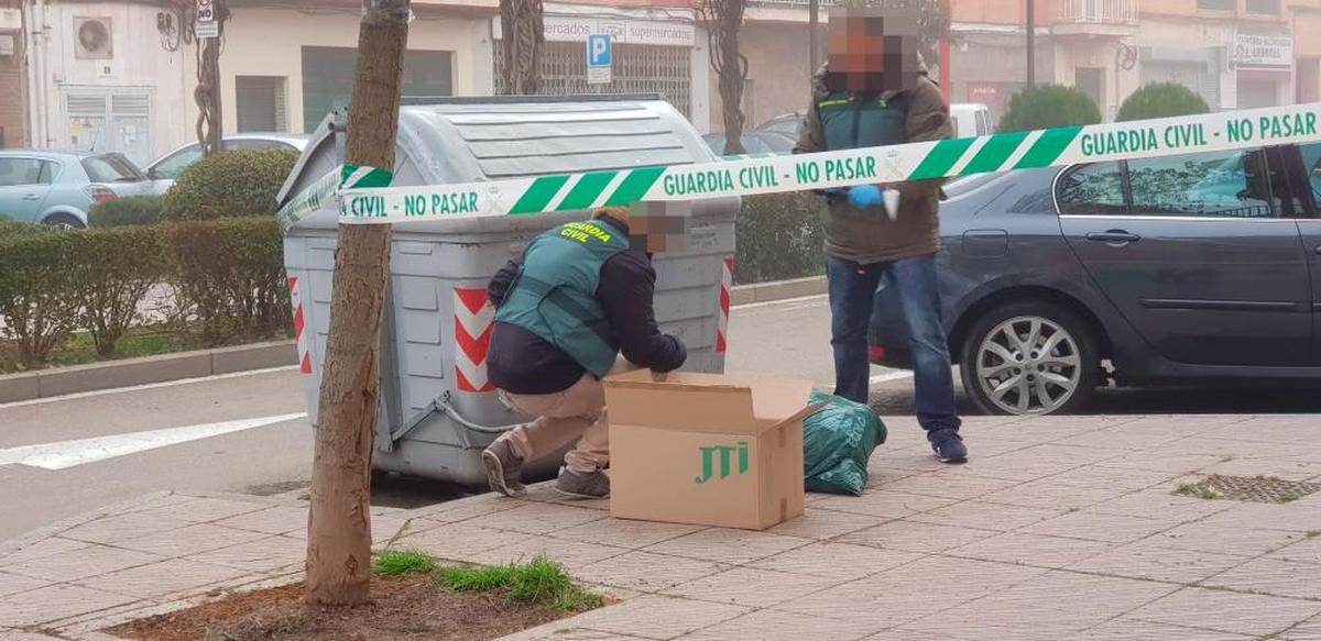 Agentes de la Guardia Civil revisan un contenedor cercano a la vivienda donde apareció una mujer muerta de manera violenta