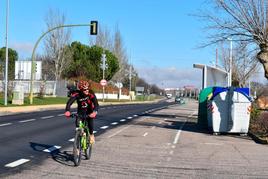 Un ciclista en el carril bici de la travesía de Aldeatejada, junto a la marquesina del autobús.