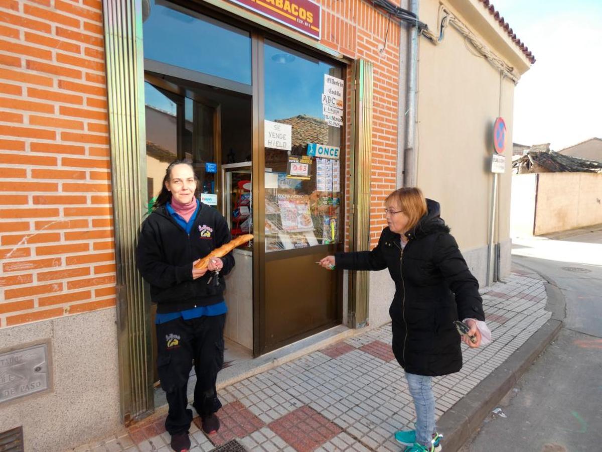 Dos vecinas se encuentran en la puerta de la tienda.