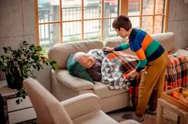 Un niño cuida a su abuelo del frío