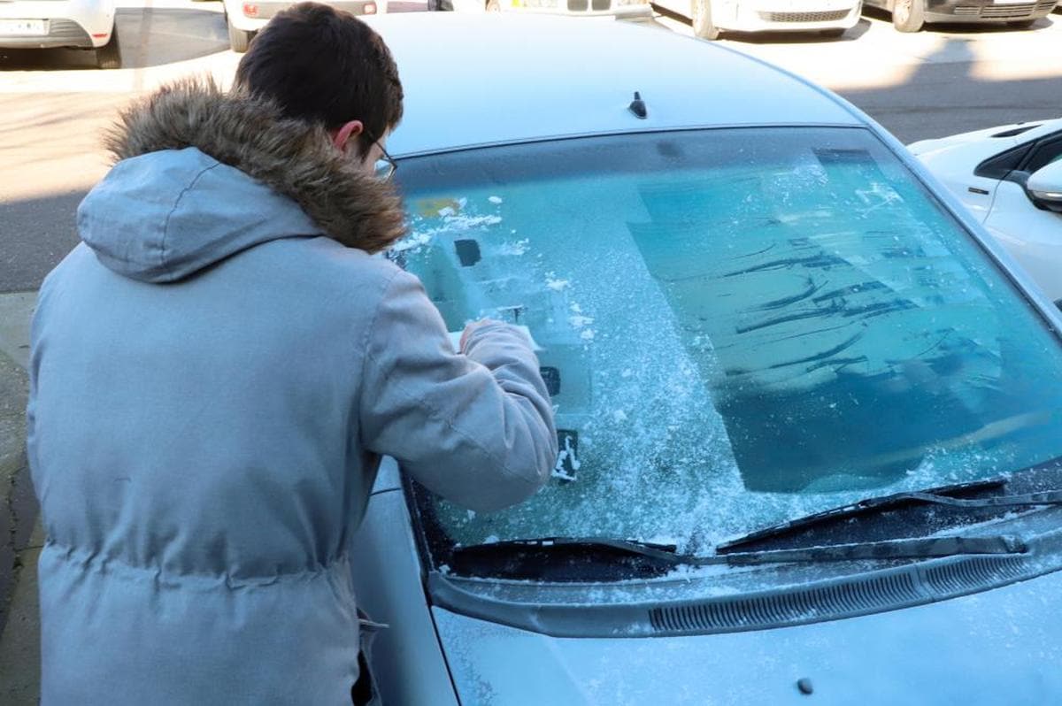 Un conductor retira el hielo de su vehículo.