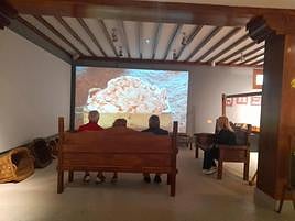 Un grupo de visitantes contempla un vídeo sentados en los grandes escaños que acoge el museo