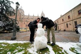 Dos jóvenes hacen un muñeco de nieve en la plaza de Anaya.