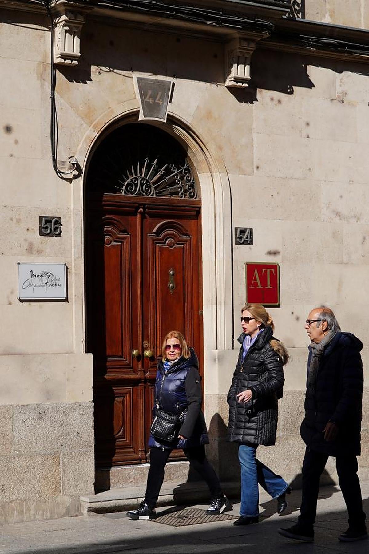 Tres personas pasean frente a la fachada de un edificio con apartamentos turísticos del centro de la ciudad.