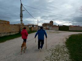 Unos vecinos de la localidad de Salmoral pasean con su perro por las inmediaciones del municipios