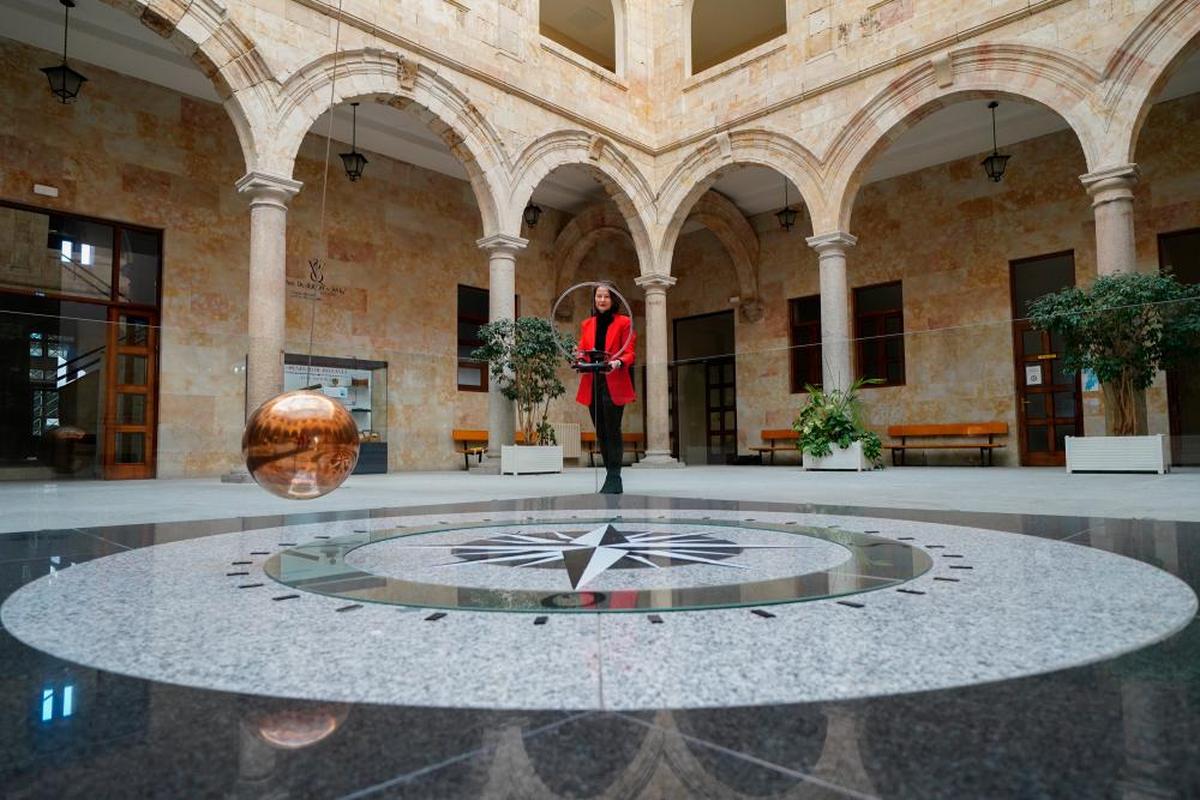 El péndulo de Foucault oscila en el patio central del Edificio Trilingüe de Físicas. En el centro, María Jesús Santos, vicedecana de la Facultad de Ciencias.