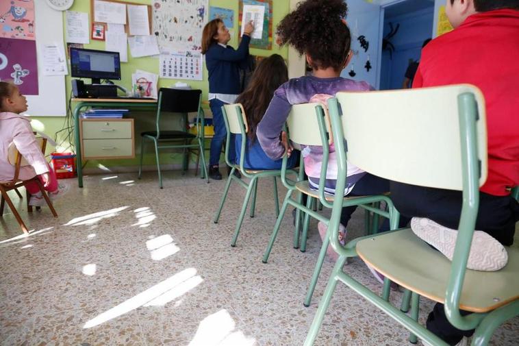 Escolares escuchando a una maestra en un aula de un centro educativo.
