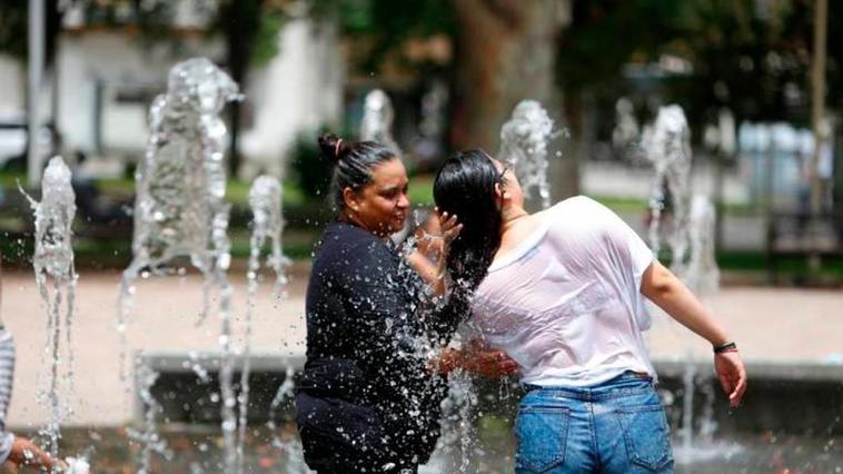 Dos mujeres se refrescan en una fuente de agua.