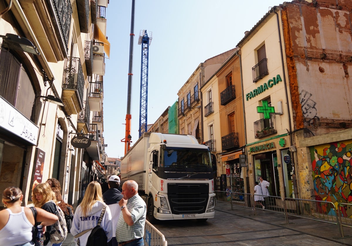 Peatones caminando por la Rúa mientras se instala una gran grúa.