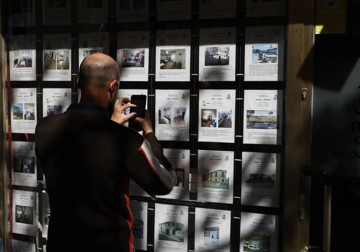 Un hombre fotografía los carteles de una inmobiliaria salmantina.