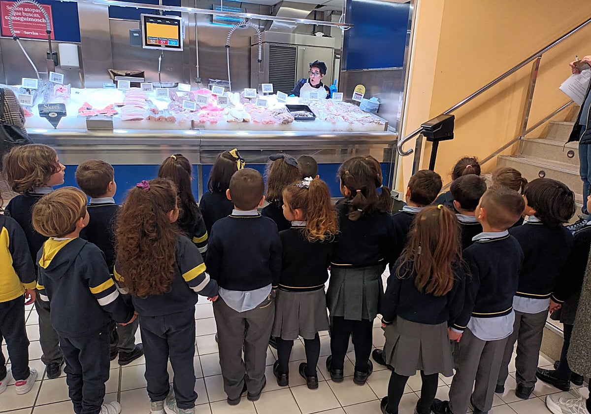 Un grupo de escolares escucha las indicaciones en la pescadería de Gadis