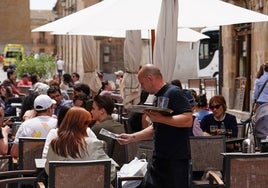 Un camarero atiende a unos clientes en una terraza en Salamanca.