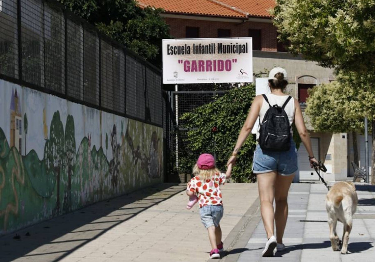 Una mujer camina junto a un perro y un niño junto al Centro Infantil de Garrido.