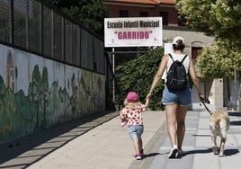 Una mujer camina junto a un perro y un niño junto al Centro Infantil de Garrido.