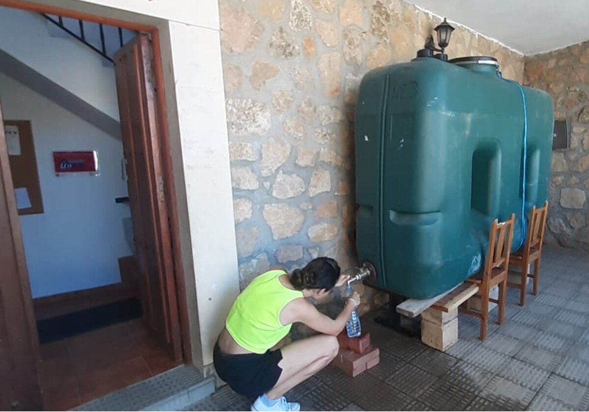 Vecina de Torresmenudas cogiendo agua de un depósito portátil.