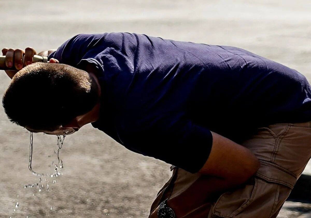 Hombre con ropa oscura refrescándose en ola de calor