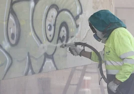 Un operario retira una pintada en la fachada de un edificio de Salamanca
